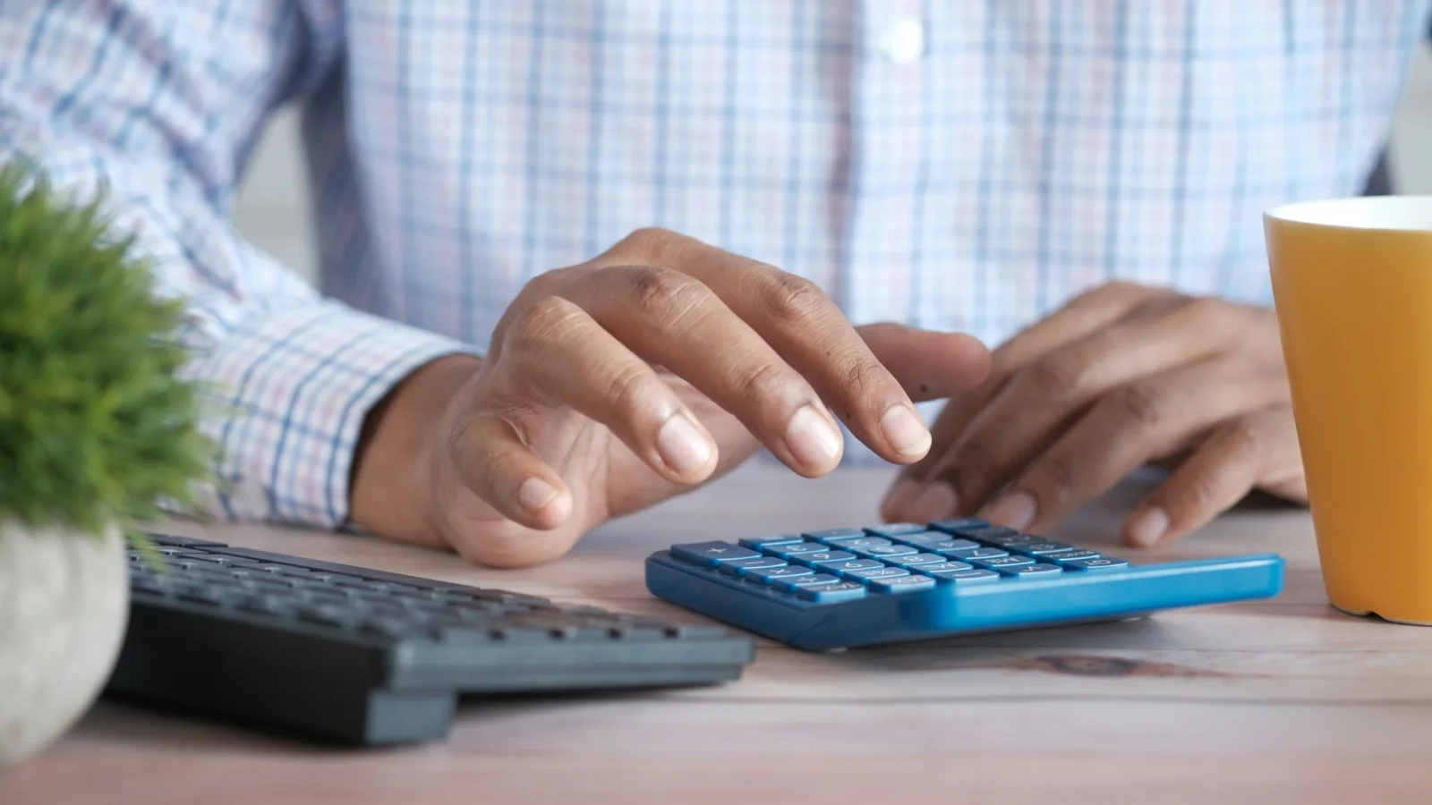 Person using a calculator while reviewing a budget